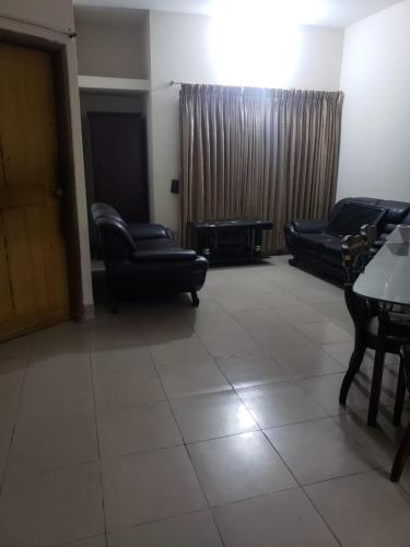 ein Wohnzimmer mit 2 Stühlen, einem Sofa und einem Tisch in der Unterkunft Lovely two bed flats by Dhaka Shahjalal Airport in Dhaka
