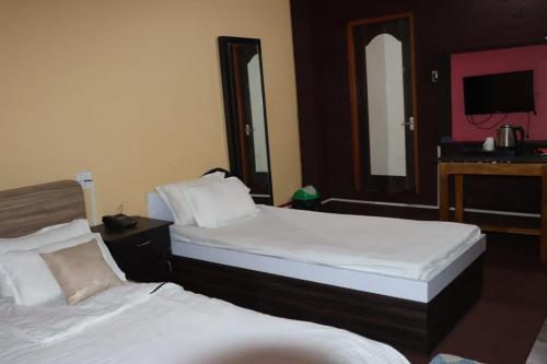 a hotel room with two beds and a tv at Holiday Inn in Kakarvitta