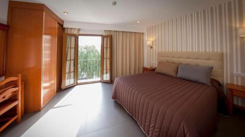 um quarto com uma cama grande e uma varanda em Hotel Rambla Emérita em Mérida