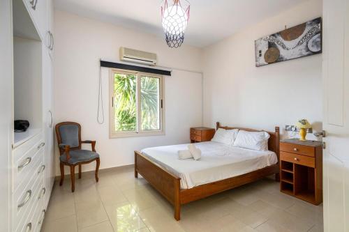 een slaapkamer met een bed, een stoel en een raam bij A villa located in the middle of the mountains .. in Trimitusa