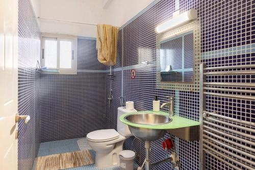 een blauw betegelde badkamer met een toilet en een wastafel bij A villa located in the middle of the mountains .. in Trimitusa