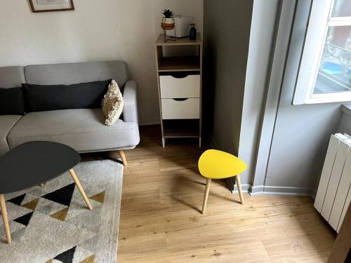 a living room with a couch and a yellow stool at Appartement centre historique Monségur in Monségur