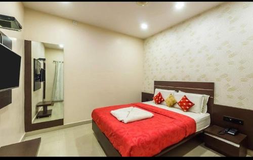 a bedroom with a bed with a red blanket at Hotel Royal Palace Mysuru in Mysore