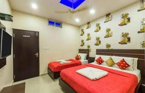 a bedroom with two beds with red sheets and a tv at Hotel Royal Palace Mysuru in Mysore