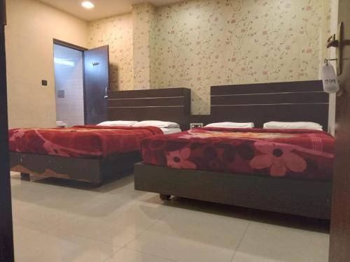 two beds in a bedroom with red sheets at Hotel Royal Palace Mysuru in Mysore