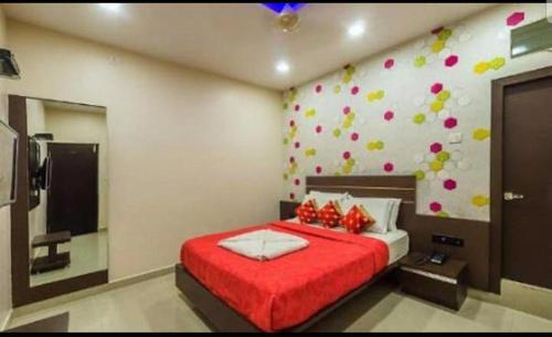 a bedroom with a red bed and a wall with a television at Hotel Royal Palace Mysuru in Mysore