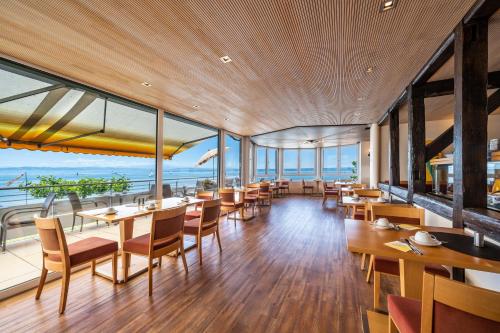 un restaurante con mesas, sillas y ventanas grandes en Gästehaus am Bodensee en Immenstaad am Bodensee