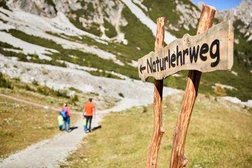 two people walking down a mountain trail with a sign at Oskar Apartments in Neustift im Stubaital