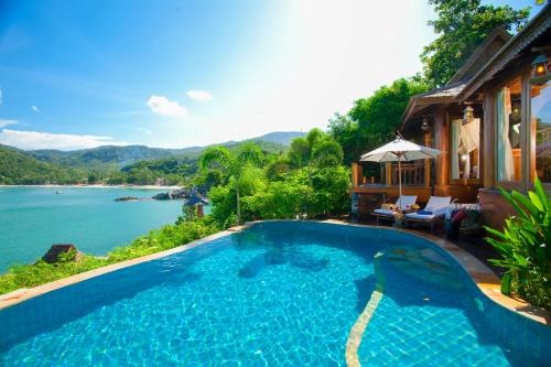 a swimming pool next to a house with a view of the water at Santhiya Koh Phangan Resort and Spa in Thong Nai Pan Noi