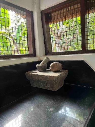 a room with a rock chair in front of windows at Puthukkeril Heritage Home in Talavadi