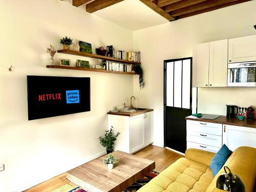 uma sala de estar com um sofá e uma televisão na parede em Vieux Marly-le-Roi - Studio bien equipé - Matelas haut qualité em Marly-le-Roi