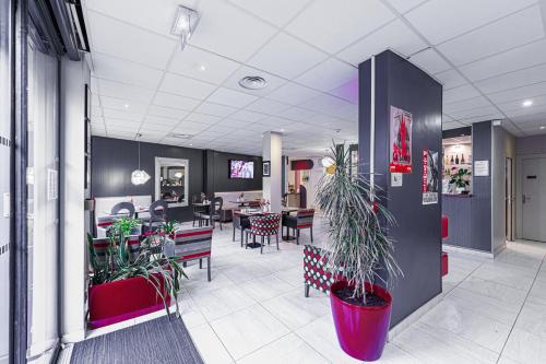 a lobby with tables and chairs and potted plants at Nyx Hôtel Indépendant in Perpignan