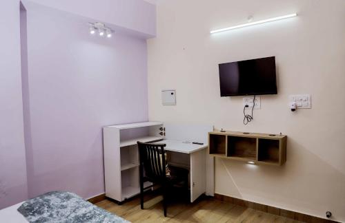 a bedroom with a desk and a tv on the wall at Bobby’s B&B in Lucknow