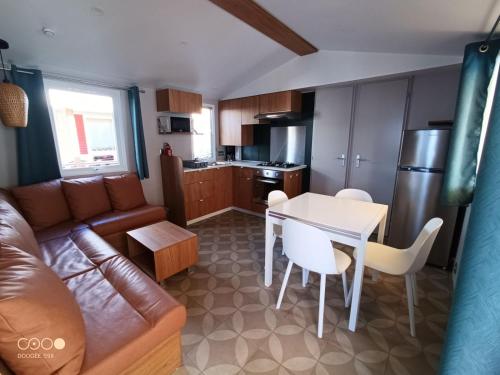 salon i kuchnia z kanapą i stołem w obiekcie camping les sables du midi w mieście Valras-Plage