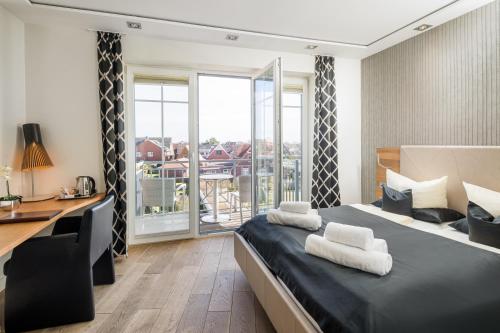 a bedroom with a bed with a desk and a balcony at Logierhus Langeoog in Langeoog