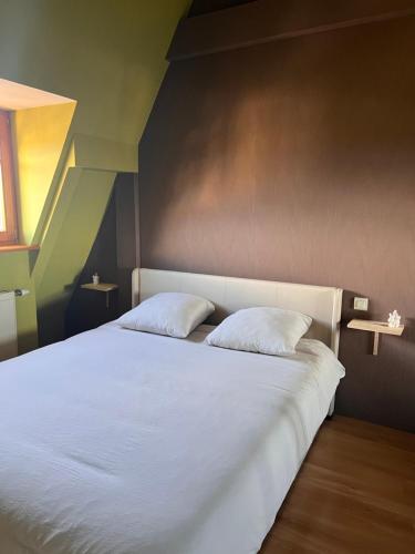 een slaapkamer met een wit bed met 2 kussens bij Duplex au cœur de Turckheim, 10 min de Colmar et place de parking in Turckheim