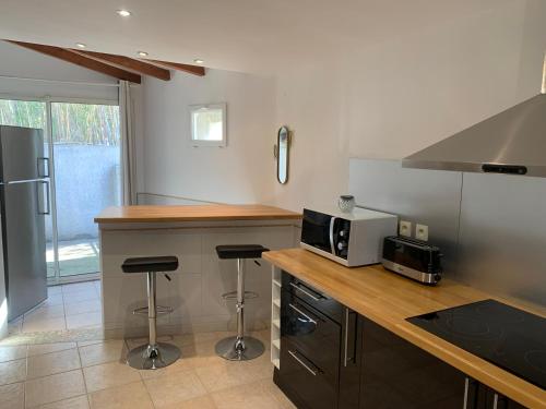 une cuisine avec un comptoir, un four micro-ondes et des tabourets dans l'établissement Mas du Roc, à Saint-Nazaire