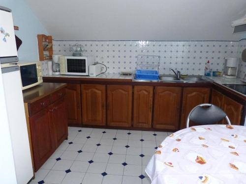 une cuisine avec des armoires en bois et un four à micro-ondes dans l'établissement APPARTEMENT AVEC TERRASSE ET BARBECUE, à Granville