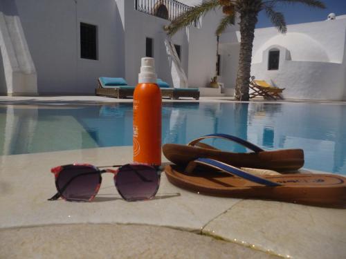 a pair of sunglasses and a bottle next to a swimming pool at Maison Leila chambres d hotes in Midoun