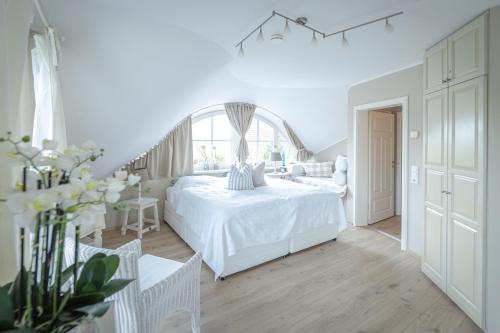 a white bedroom with a white bed and a window at Reethaus Glowe in Glowe
