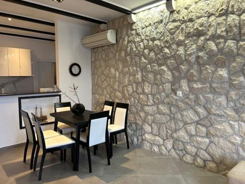 comedor con pared de piedra, mesa y sillas en Perina Apartment - free parking, en Dubrovnik