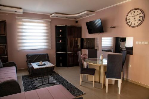 een woonkamer met een tafel en een klok aan de muur bij Apartman Lara in Kuršumlija