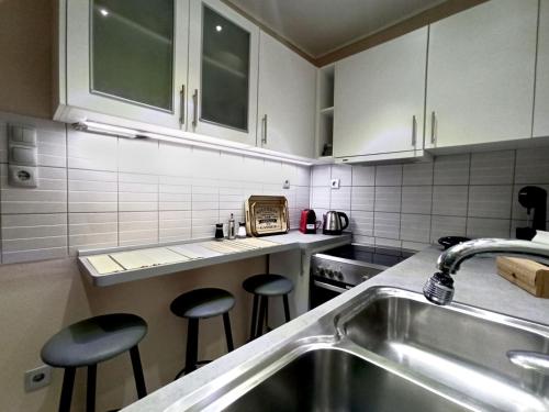 uma cozinha com um lavatório e dois bancos de bar em Kallaris Deluxe House em Tessalónica