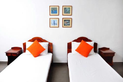 two beds with orange pillows in a room at Sea View Hotel in Colombo