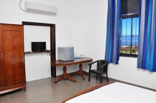 Habitación con escritorio, cama y ventana. en Sea View Hotel en Colombo