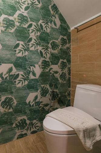a bathroom with a toilet and a green and white tiled wall at MODERN - CITY CENTER, Phrom Phong BTS, Em District, Terminal 21, MAX 14 People in Bangkok