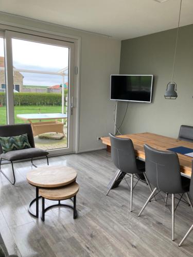 uma sala de estar com uma mesa e cadeiras e uma televisão em Vissers Huus Hollum Ameland em Hollum