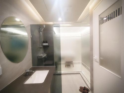 ein Bad mit einem Waschbecken und einem Spiegel in der Unterkunft 인천 연수 블루버드호텔 Bluebird Hotel in Incheon
