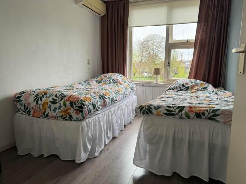 two beds in a room with a window at Our home, your home, close to Amsterdam in Nederhorst den Berg