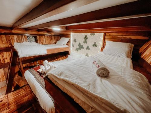 two beds in a room with wooden walls at Dav-Venture in Labuan Bajo
