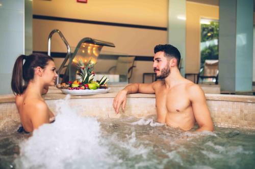 Ein Mann und eine Frau sitzen in einer Badewanne in der Unterkunft Rizzi Aquacharme Hotel & Spa in Boario Terme