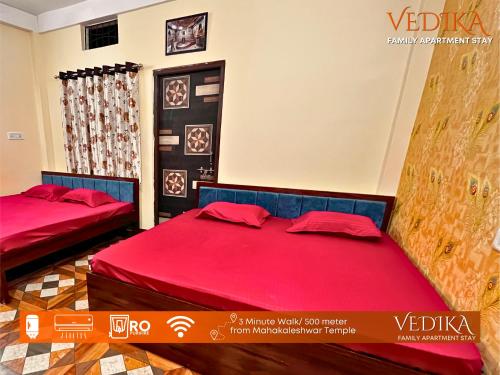 two beds in a room with red sheets at Vedika Yatri Grah - Entire Apartment in Ujjain