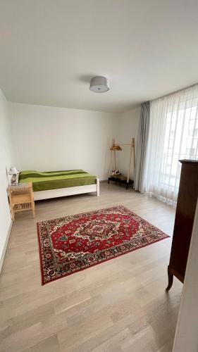 a room with a bed and a rug on a floor at Hugo apartment & parking in Rīga