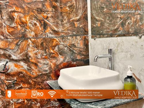 a bathroom with a sink and a marble wall at Vedika Yatri Grah - Entire Apartment in Ujjain