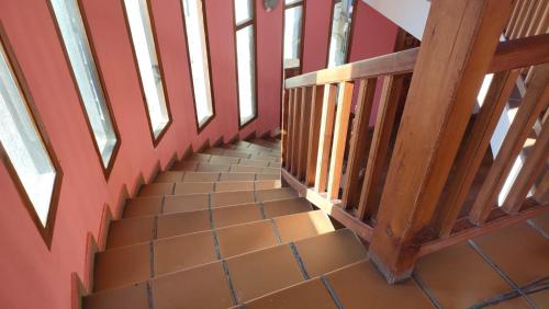 a staircase in a house with red walls and wooden railings at Alojamientos La Dehesa in El Berrueco