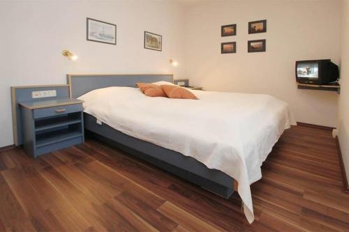 ein Schlafzimmer mit einem großen Bett, einem Nachttisch und einem TV in der Unterkunft Yachthafenresidenz - Wohnung 9102 / 878 in Kühlungsborn