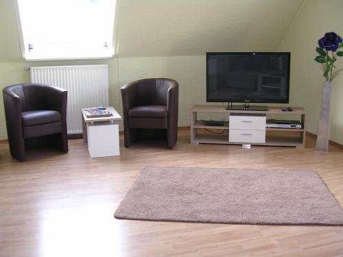 a living room with two chairs and a flat screen tv at Ferienwohnung Müller Bad Segeberg in Bad Segeberg