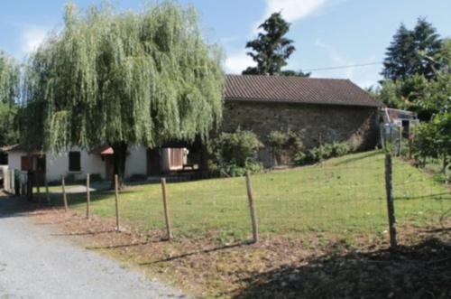 uma cerca em frente a uma casa com uma árvore em latterie em Dournazac