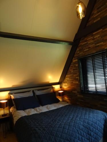 een slaapkamer met een bed en een bakstenen muur bij B&B Geniet Nátuurlijk in Wapserveen