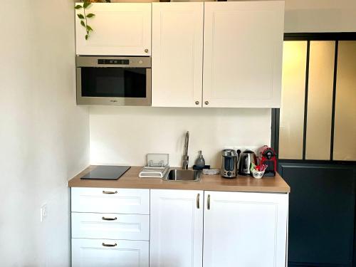 une cuisine avec des armoires blanches et un évier dans l'établissement Studio au vieux Marly-le-Roi - Bien equipé - Matelas de qualité - 7min du Train vers Paris, à Marly-le-Roi