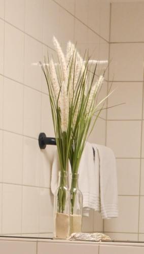 a vase with grass in it on a shelf in a bathroom at Nordic Avantage Hotel in Kiel