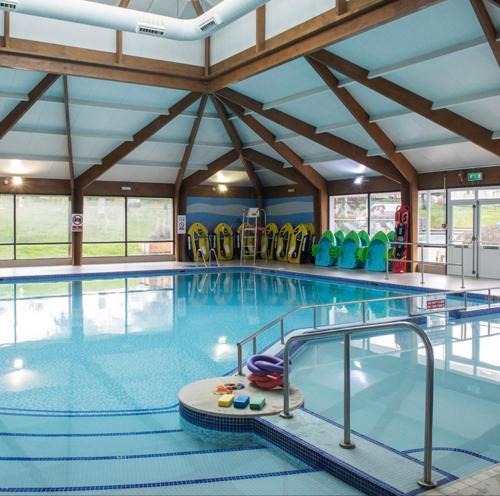 una gran piscina cubierta con un gimnasio con sillas verdes en 21 Riverview, Allhallows, en Rochester