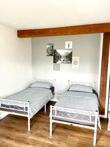 2 letti in una camera con pareti bianche e pavimenti in legno di Ferienwohnung Herbolzheim a Herbolzheim