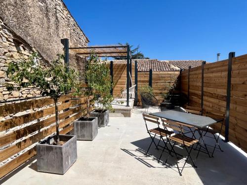 un patio con mesa y sillas junto a una pared en Appartement cosy avec terrasse, en Saint-Gervasy