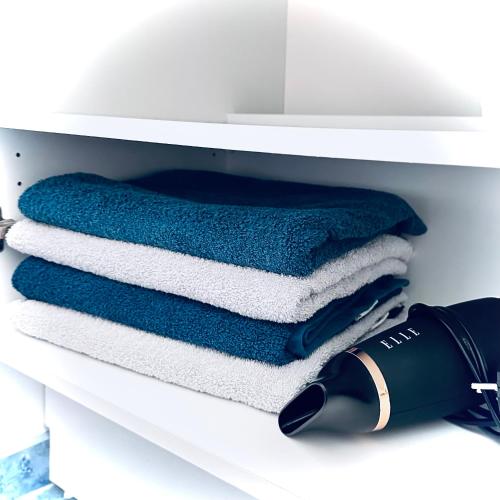 - une étagère avec 4 serviettes dans une salle de bains blanche dans l'établissement Sweet apartment in front of Disneyland's castel, à Montévrain