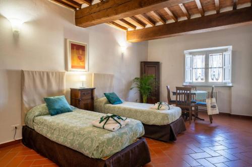 a room with two beds and a dining room with a table at La Dimora nell'Anfiteatro Superior room and apartment Lift Air conditioning in Lucca